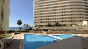 A hotel with a pool area, a view of the ocean, and a multi-story building with balconies.