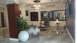 A modern lobby with a large potted plant, a seating area with a round table, and a decorative wall with framed artwork. - Grand Hyatt Hotels  (Owerri)