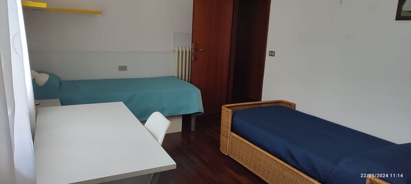 A room with two beds, a table, and a radiator.