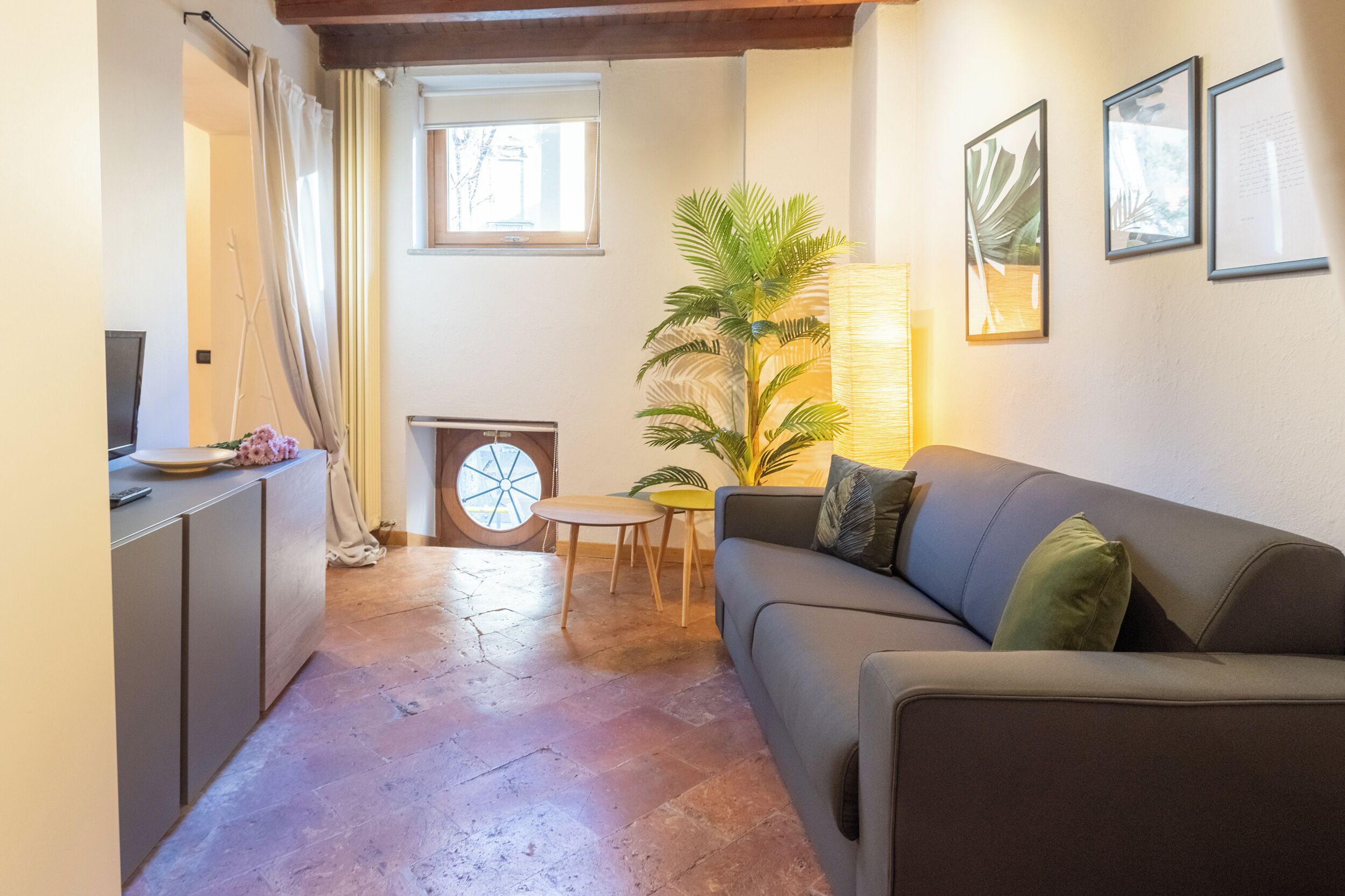 A cozy living area with a sofa, a small table, a potted plant, and a fireplace.