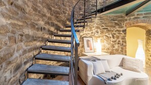A stone-walled room with a modern staircase, a white sofa, and a framed picture on the wall. - Ice Queen Chamber by Rent all Como (Como)