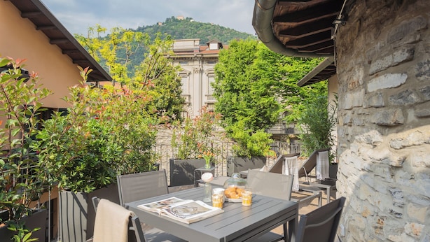 An outdoor patio with a table set for dining, surrounded by stone walls and greenery. - Ice Queen Chamber by Rent all Como (Como)