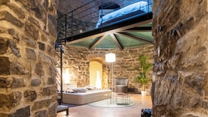 A stone-walled room with a bed, a chair, and a hanging lamp. - Ice Queen Chamber by Rent all Como (Como)