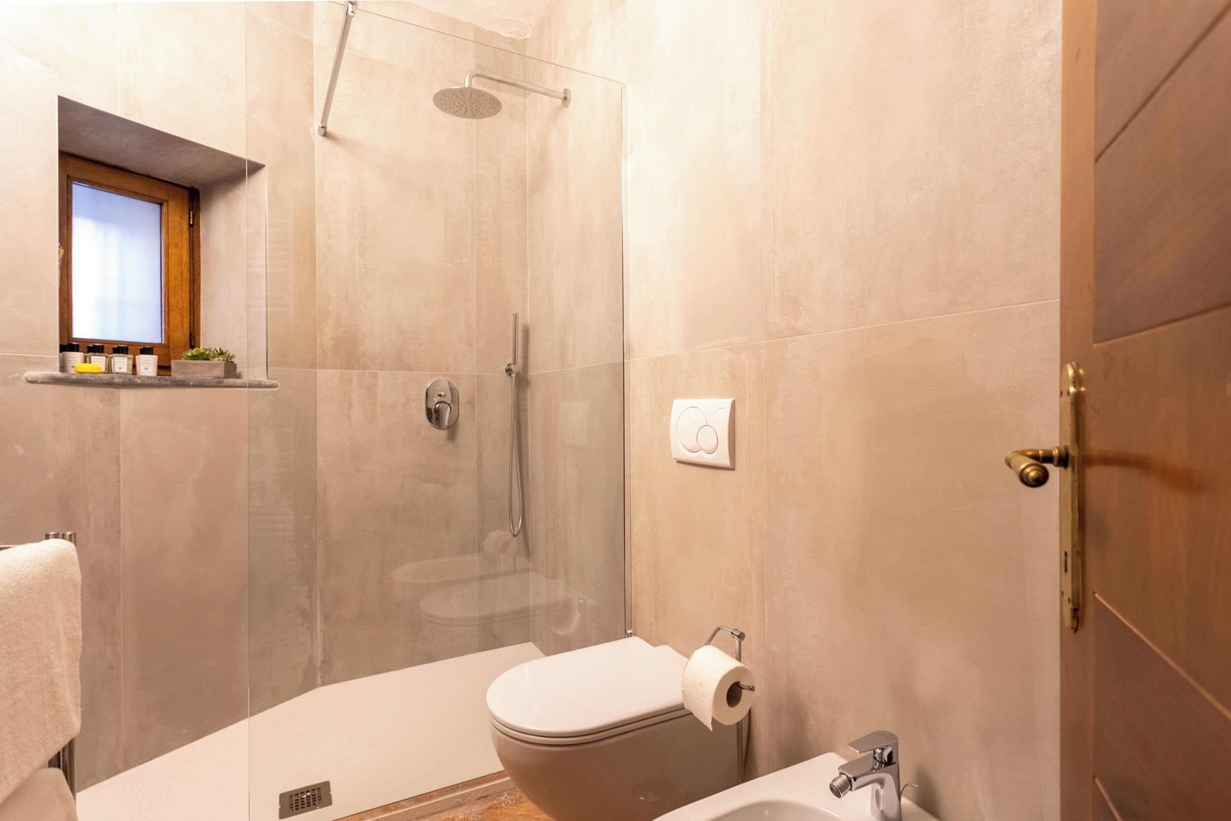 Un baño moderno con ducha envuelta en vidrio, inodoro y bañera.
