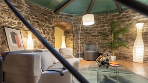A cozy living room with a stone wall, a round glass coffee table, a sofa, and a potted plant. - Ice Queen Chamber by Rent all Como (Como)