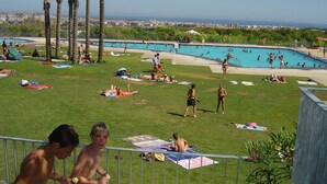 A pool area with a view of the city, palm trees, and people sunbathing. - Good Standard Furnished Chalet on Nice Park (Castellet i la Gornal)