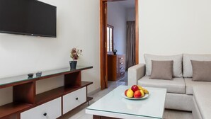 A modern living room with a flat-screen TV, a glass coffee table with fruit, a sofa, and a wooden TV stand. - Lazur Sea & City Apartment's - El Hadaba, Hurghada - Egypt (Hurghada)