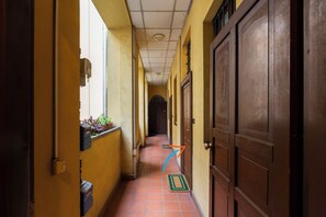 A narrow hallway with tiled flooring, wooden doors, and yellow walls. - notaMi - UP&DOWN Monte Nero (Milan)