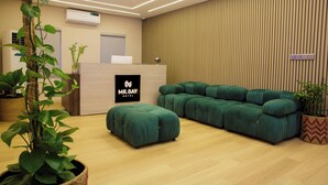 A modern hotel reception area with a green sofa, a reception desk, and potted plants. - Mr Bay Hotel (Lagos)