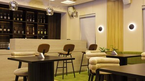 A bar area with multiple tables and chairs, a shelf with bottles, and pendant lighting. - Mr Bay Hotel (Lagos)