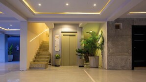 A modern hotel lobby with a staircase, a reception desk, and potted plants. - Mr Bay Hotel (Lagos)