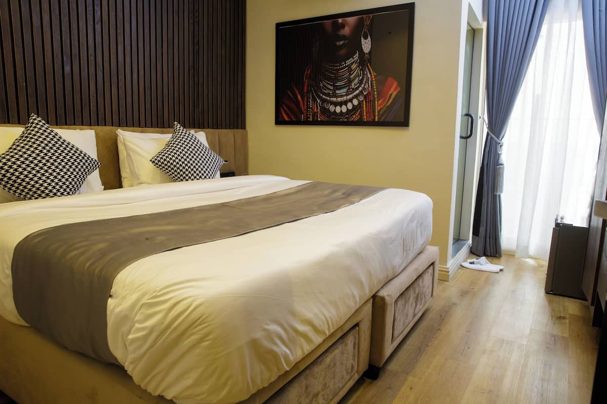 A neatly made bed with a gray throw, a wooden headboard, and patterned pillows.