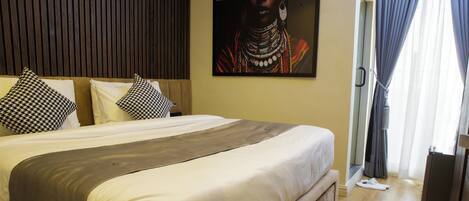 A neatly made bed with a gray throw, a wooden headboard, and patterned pillows.