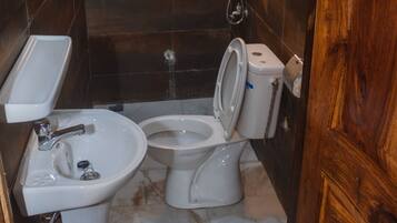 A compact bathroom with a sink, toilet, and shower.
