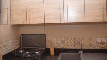 A kitchen with wooden cabinets, a gas stove, a sink, and patterned backsplash tiles.