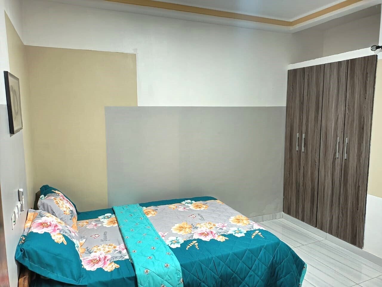 Een slaapkamer met een bed, een kledingkast en een plafond met een lamp.