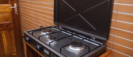 A kitchen with a gas stove, wooden cabinets, and a tiled backsplash.