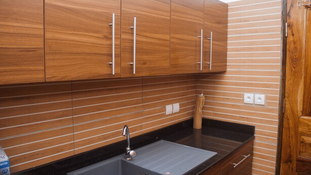 Een keuken met houten kastjes, een zwart aanrecht en een roestvrijstalen spoelbak.
