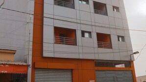 Een meerlaags gebouw met een platte gevel, grote ramen en een groene poort ervoor.