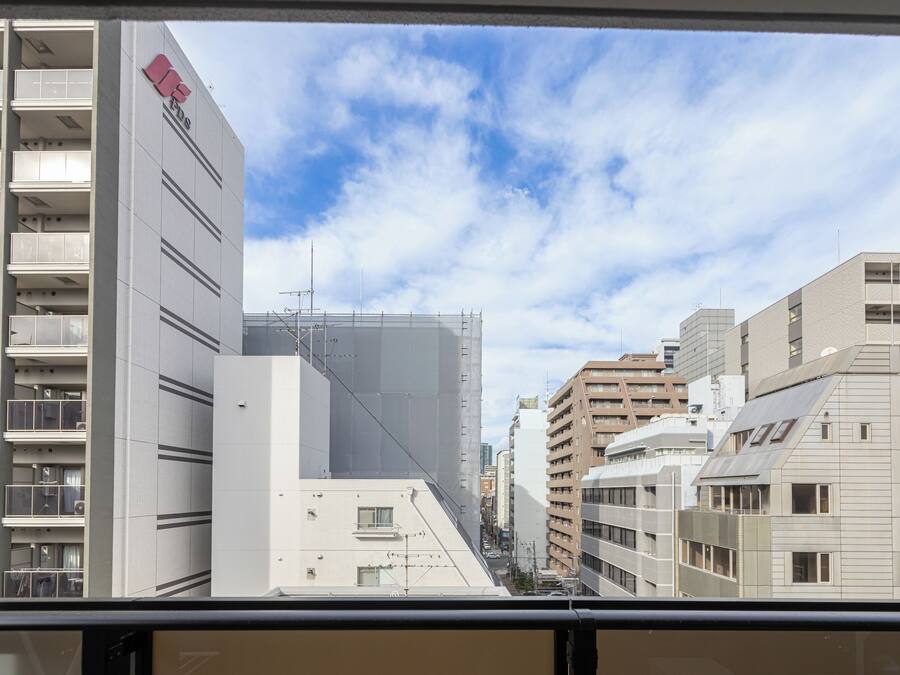 Vista de un paisaje urbano con edificios modernos, incluyendo un edificio blanco destacado con un logotipo rojo a la izquierda.