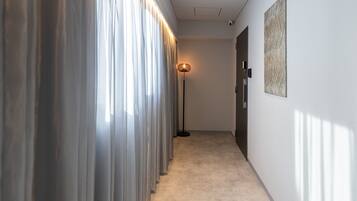 A hallway with a floor lamp, a door, and a wall-mounted artwork.