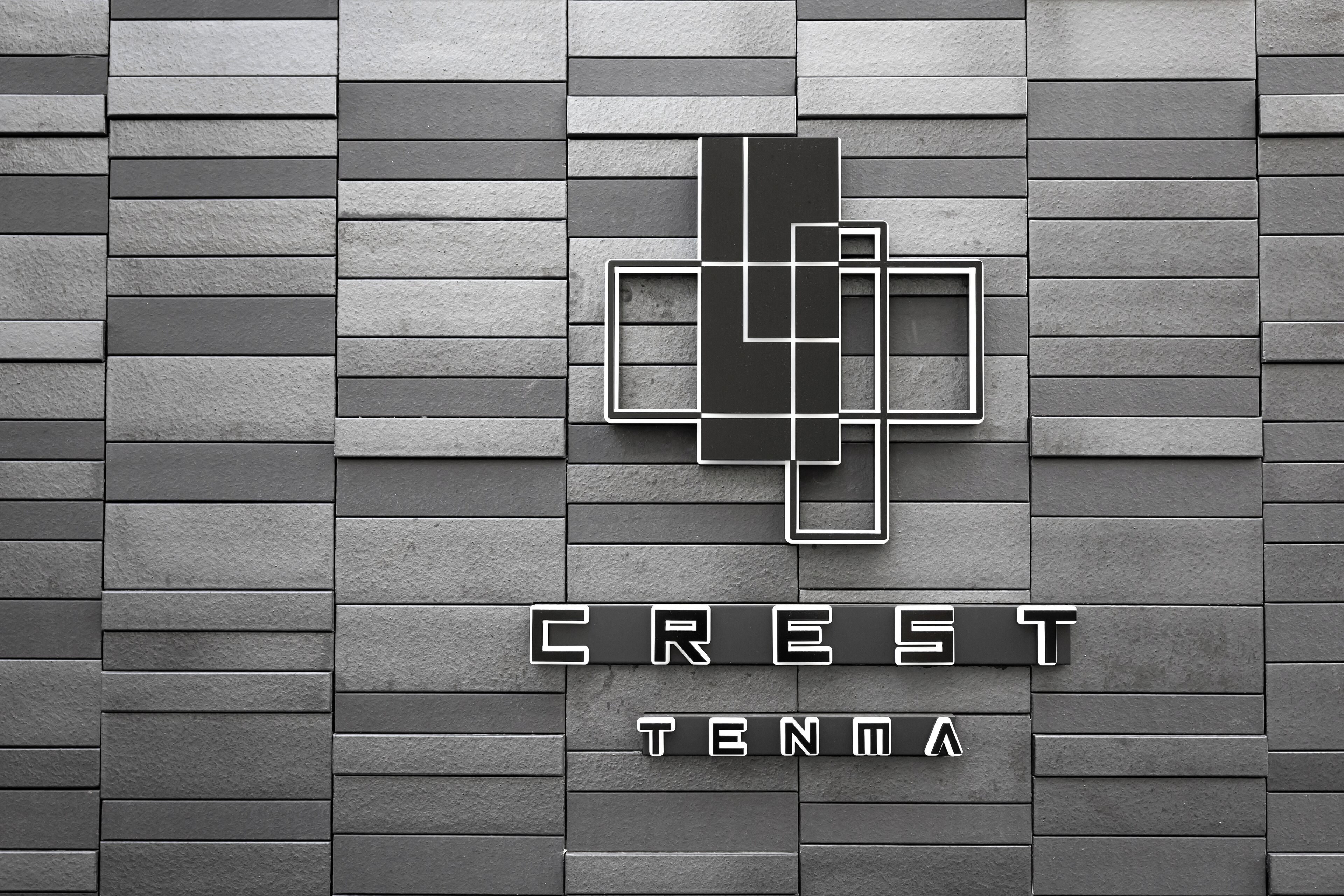 A logo with the text "CREST TENMA" on a textured wall.