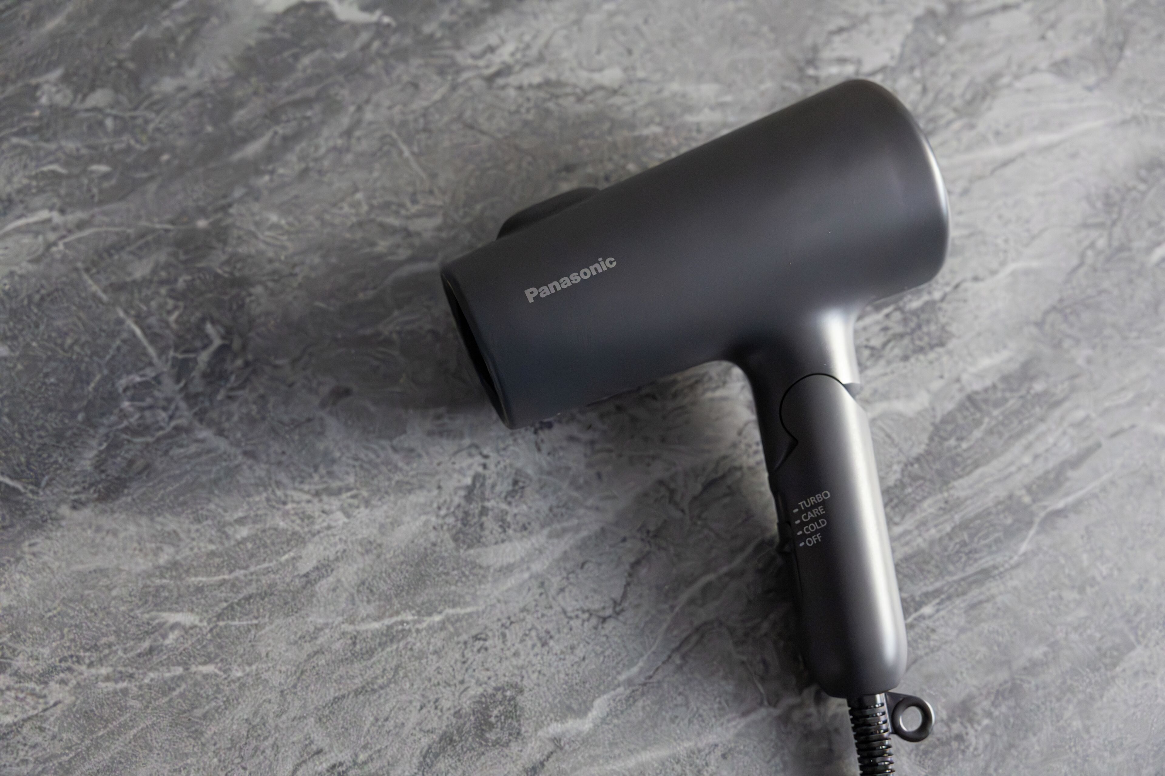 Un sèche-cheveux Panasonic posé sur une surface grise texturée.