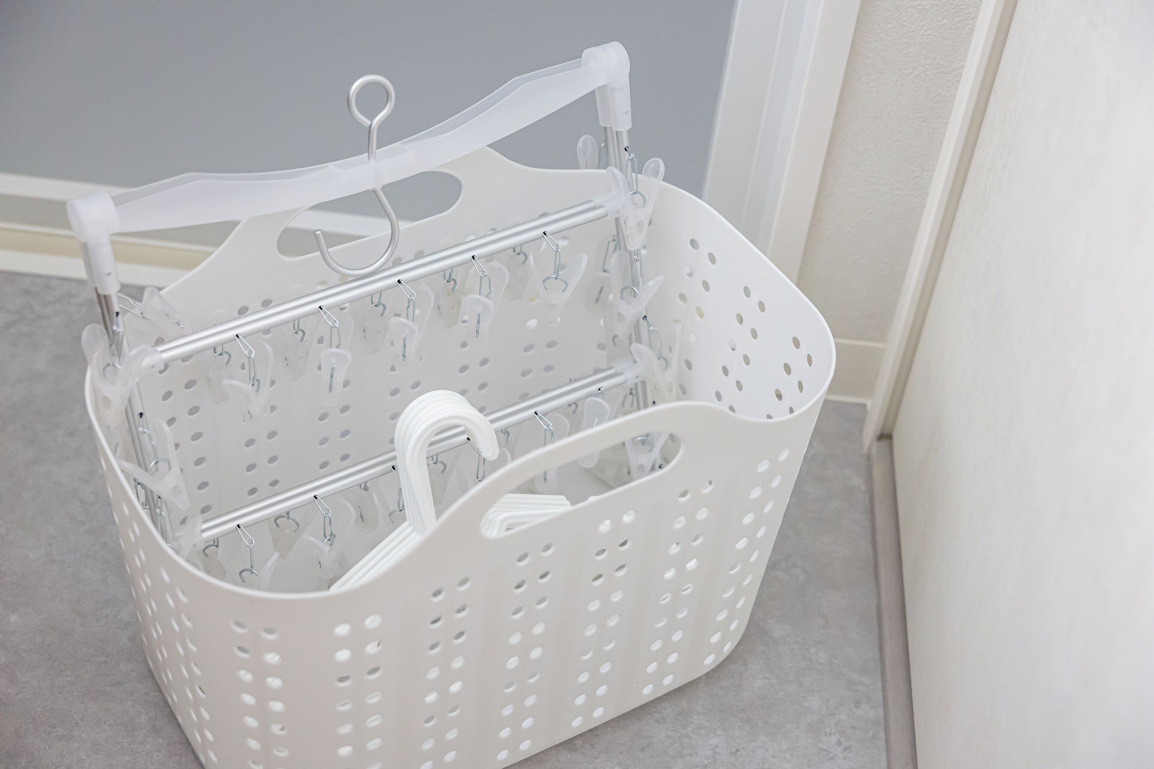 A white plastic basket with multiple compartments and hooks, likely used for organizing laundry or storage.