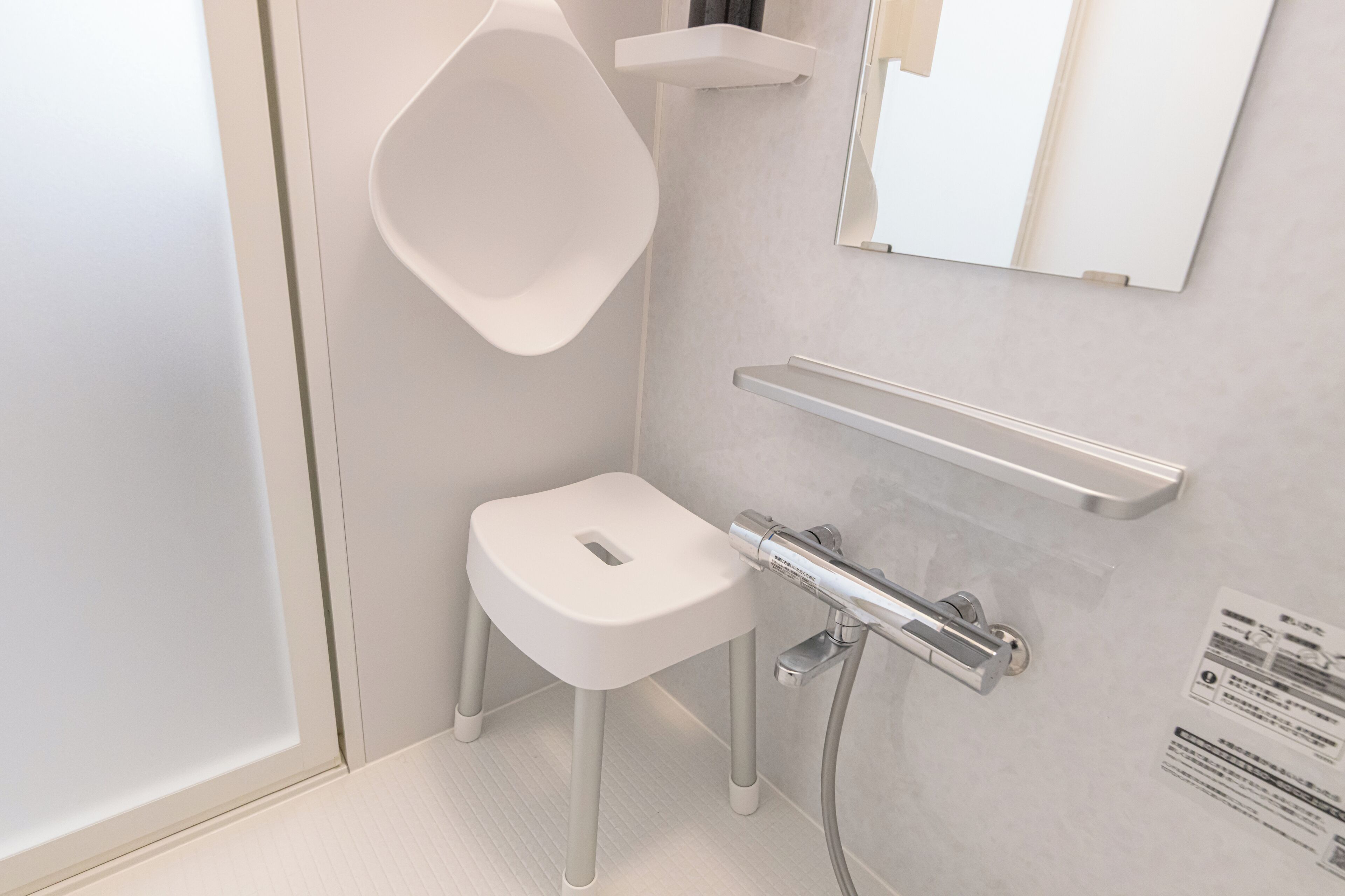 Ein modernes Badezimmer mit einem weißen Waschbecken auf Säule, einem wandmontierten Spiegel und einem chromfarbenen Handtuchhalter.