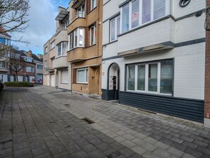 A row of townhouses with a paved street, a 'For Sale' sign, and a 'No Parking' sign.