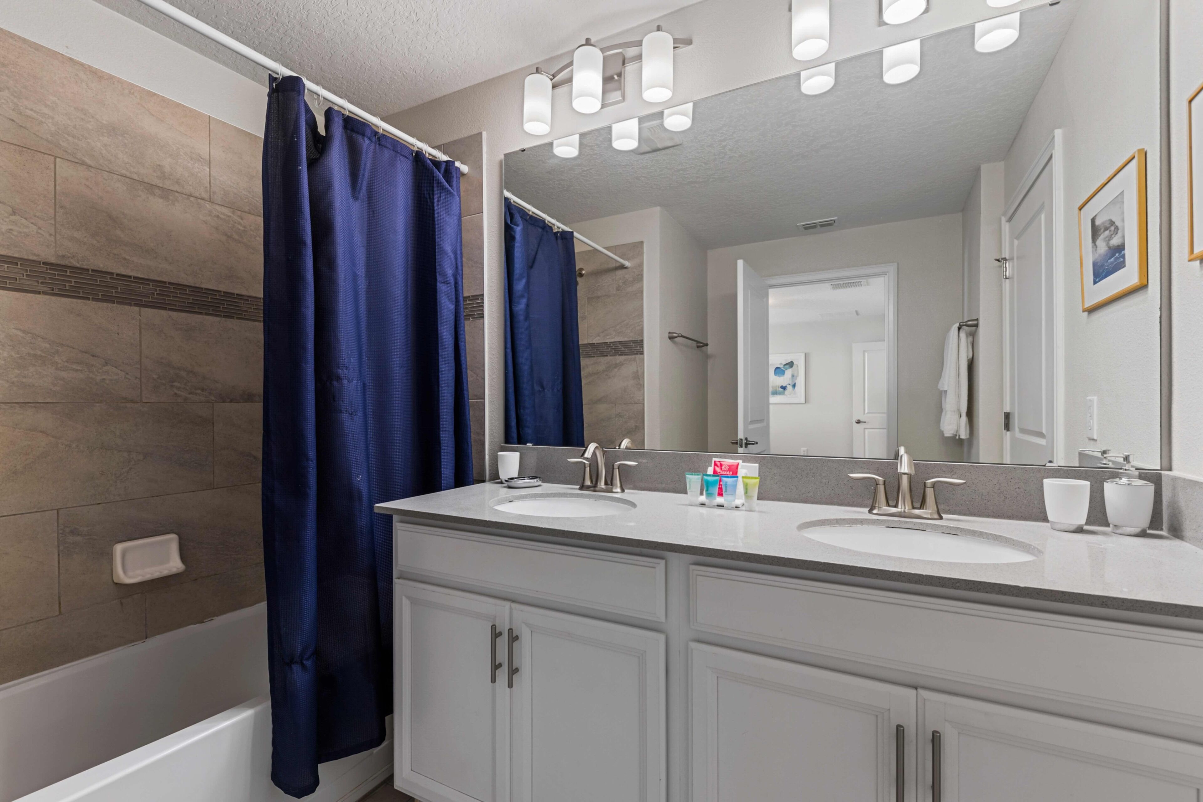 A bathroom with two sinks, a bathtub, and a shower curtain.