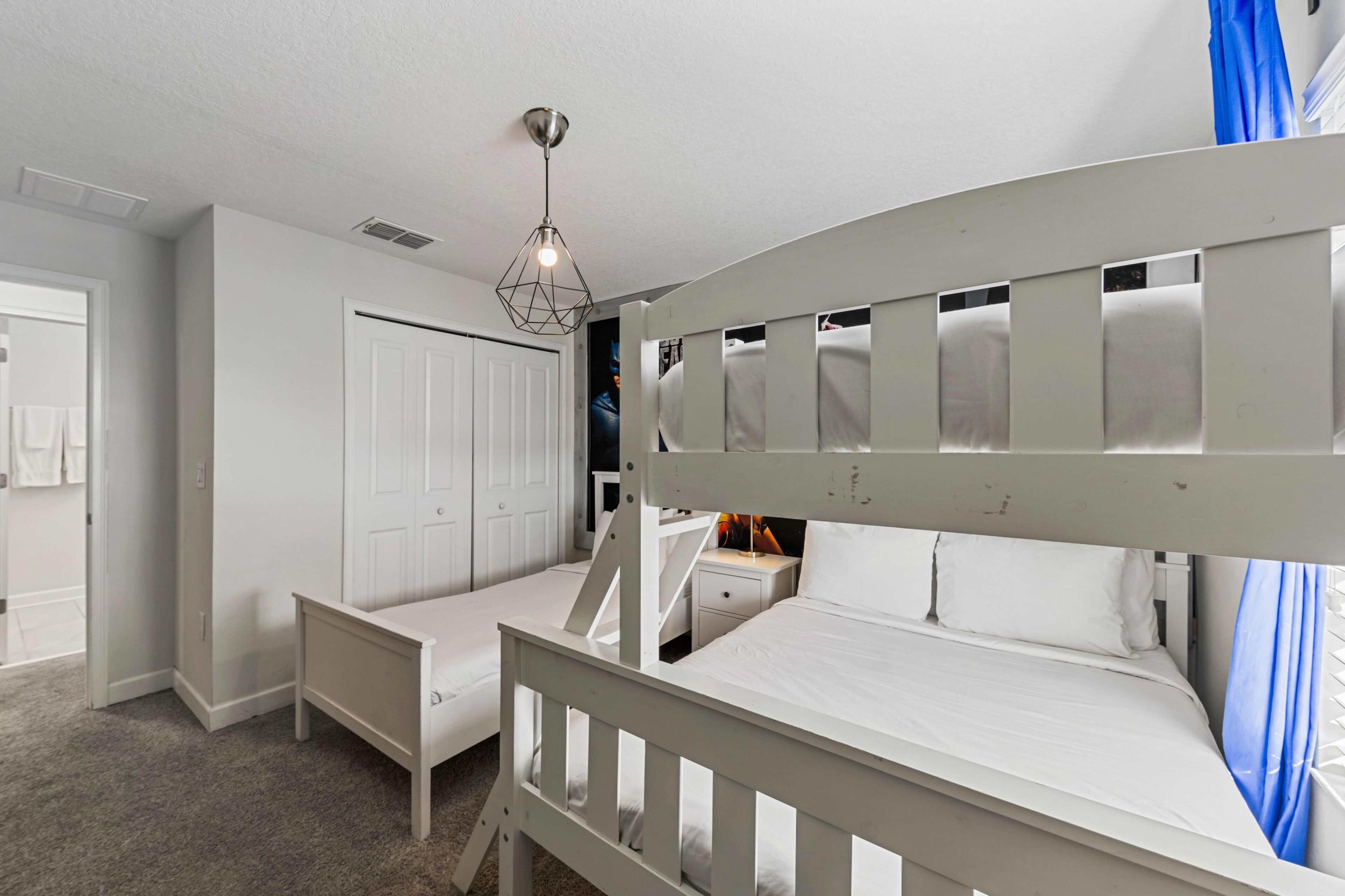 A bedroom with a bunk bed, a desk, and a wardrobe.