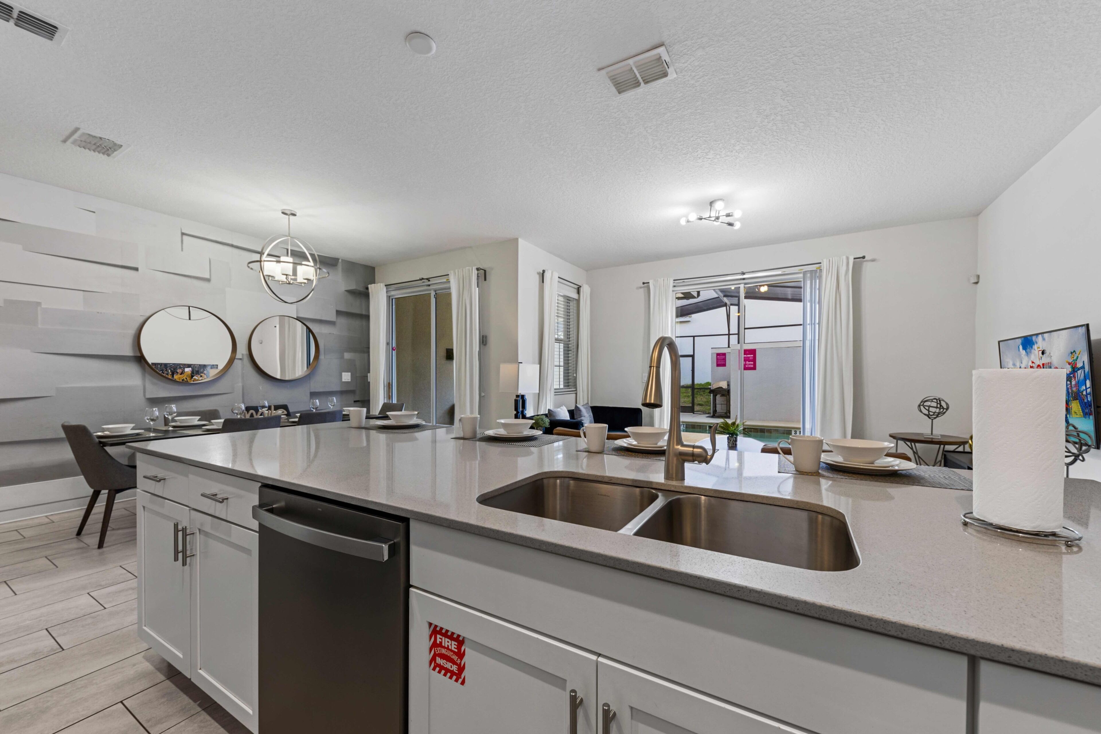 A modern kitchen with a central island, stainless steel sink, and a dishwasher.
