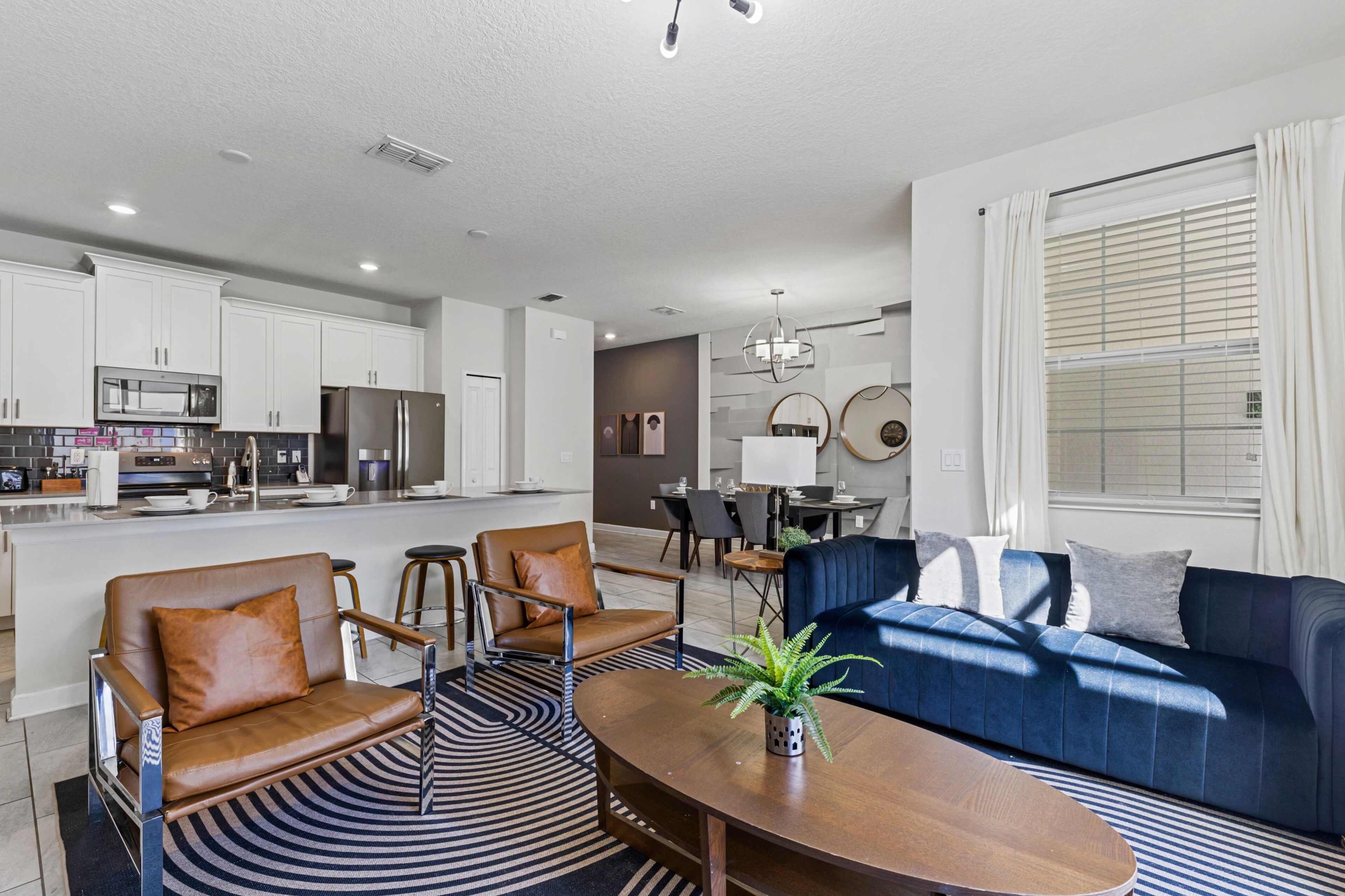 A modern living room with a blue sofa, brown leather chairs, a wooden coffee table, and a patterned rug.