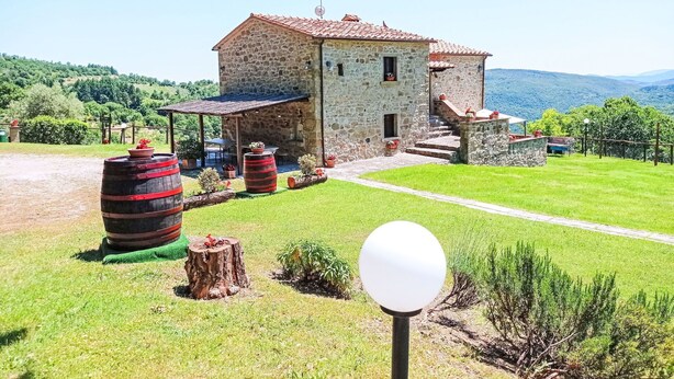 A stone building with a red-tiled roof, surrounded by a well-maintained lawn and several large barrels. - Stunning private villa for 8 people with WIFI, private pool, patio and pets allowed (Cortona)