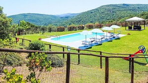 A swimming pool with lounge chairs and umbrellas, surrounded by a fenced area with a view of green hills. - Stunning private villa for 8 people with WIFI, private pool, patio and pets allowed (Cortona)