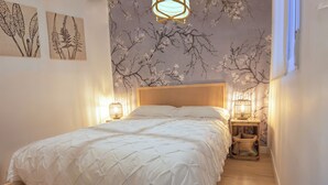 A bedroom with a bed, two wall-mounted lamps, and a floral wall mural. - A cozy space in Chamberí (Madrid)