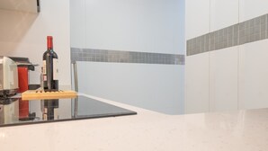 A kitchen with a wine bottle on the counter, a red appliance, and a tiled backsplash. - A cozy space in Chamberí (Madrid)