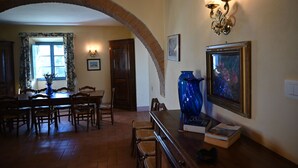 Un área de comedor con un arco de ladrillo, muebles de madera y un florero sobre la mesa.