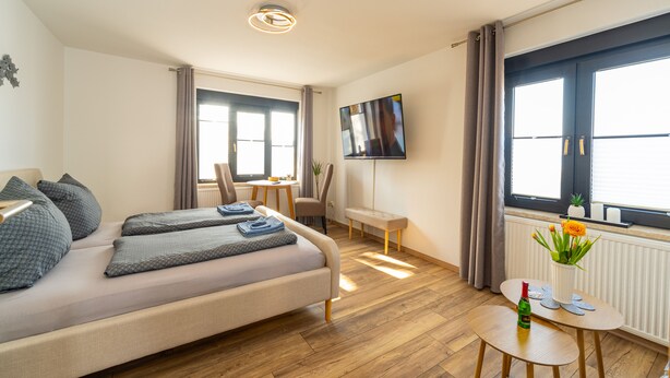 Et moderne hotelværelse med seng, skrivebord, fjernsyn og et vindue med gardiner.