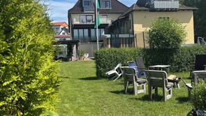Et boligområde med en velholdt græsplæne, udendørs møbler og et flagstang med et flag.