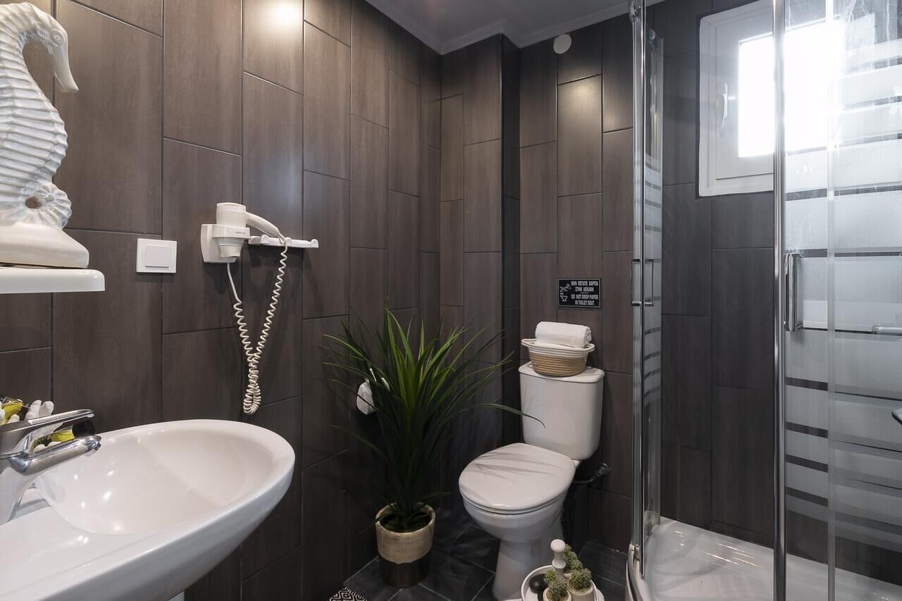 Une salle de bain moderne avec un lavabo blanc, des toilettes et un espace douche.