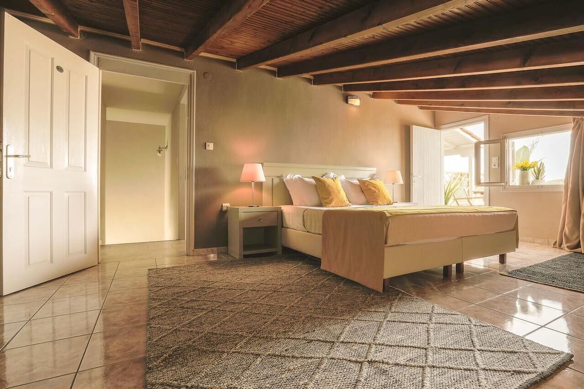 A bedroom with a bed, nightstand, and a window with curtains.