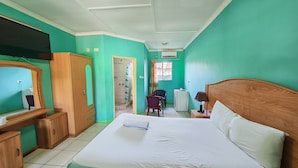 Ein Hotelzimmer mit Bett, Holzschrank, Schreibtisch und Duschbereich.