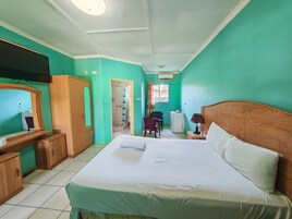 Habitación de hotel con cama, armario de madera, escritorio y zona de ducha.