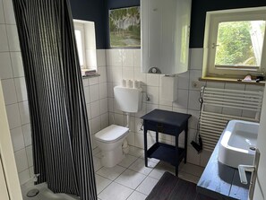 Une petite salle de bain comprenant des toilettes, un lavabo, une fenêtre et un radiateur.