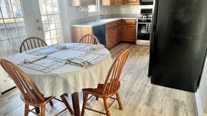 Cucina con mobili in legno, un frigorifero nero e un tavolo da pranzo con sedie.