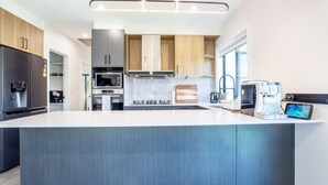 A modern kitchen with a central island, built-in appliances, and a large window providing natural light. - Modern 3B house, pet friendly close nature reserve (Throsby)