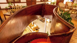 A curved wooden staircase with red steps leading to a lower level. - amã Stays & Trails Hathikuli, Assam (Bokakhat)