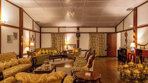 A traditional living room with a sofa set, armchairs, a coffee table, and a sideboard with decorative items. - amã Stays & Trails Hathikuli, Assam (Bokakhat)